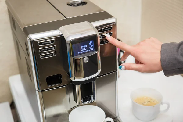 Дівчина обирає спосіб приготування кави на кавовій машині. Жіноча рука натискає кнопку на кавоварці  . — стокове фото