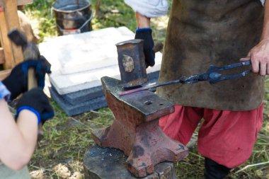 Forge. Demirci, ısıtılmış metali örse balyozla işliyor. Bir demircimanuel çalışma.