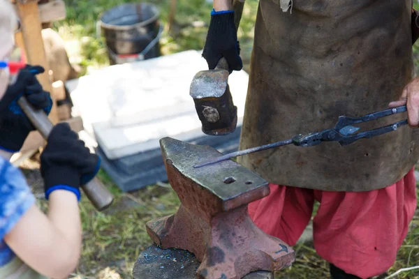 Forge. The blacksmith processes the heated metal with a sledgehammer on the anvil. Manual work of a blacksmith. — Stock Photo, Image