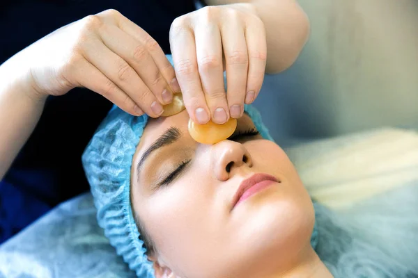 Cosmetic facial massage. Treatment of the skin with a semiprecious stone. Facial massage yellow nevritom. — Stock Photo, Image