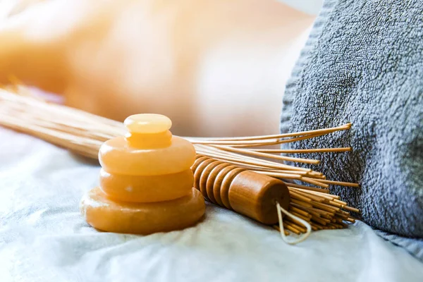 Masaj aksesuarı. Taş sarısı yeşim taşı ve bambu çırpıcıları yatay kızların arka planında masaj için..