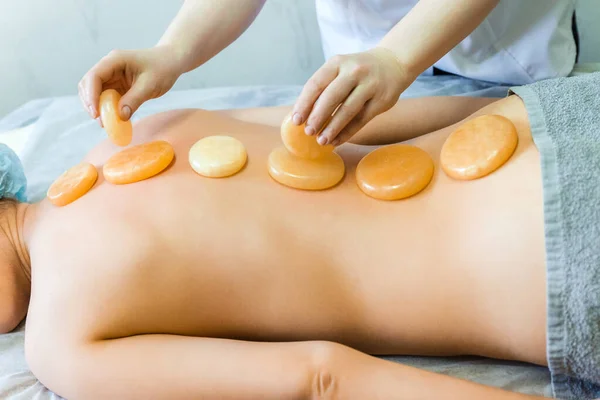 Young girl lying on table in Spa. Yellow jade for stone therapy lies on the spine along the back. — Stock Photo, Image