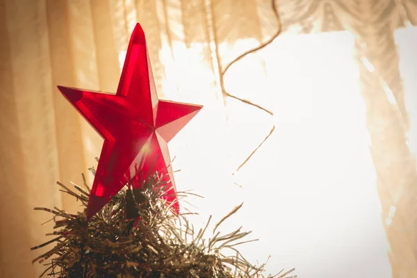 Albero di Natale decorato. Grande stella rossa sopra l'albero di Natale. Morbida attenzione alla luce solare dalla finestra . — Foto Stock