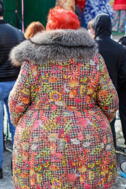 10.03.2019 yıl. Novokuznetsk 'te. - Rusya. Kürk yakalı, kızıl saçlı, güzel renkli ceketli tombul bir kadın kalabalıkta sırtı kameraya dönük duruyor..