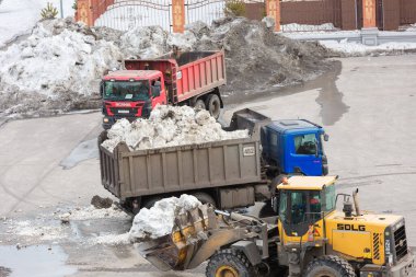 Novokuznetsk 'te. - Rusya. 09.04.2020. Kardan bölgeyi ağır ekipmanlarla temizlemek ve kamyonlara yüklemek. Yazı.