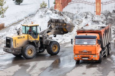 Novokuznetsk 'te. - Rusya. 09.04.2020. Kardan bölgeyi ağır ekipmanlarla temizlemek ve kamyonlara yüklemek. Yazı.