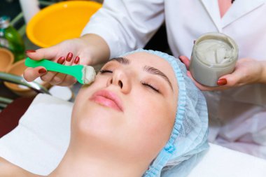 Güzellik uzmanı, yüzün derisini temizlemek için özel bir omuz bıçağı tutuyor.