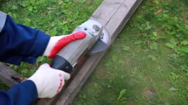 İş eldivenli bir erkek, elektrikli bir aletle tahta bir tahtayı parlatır..