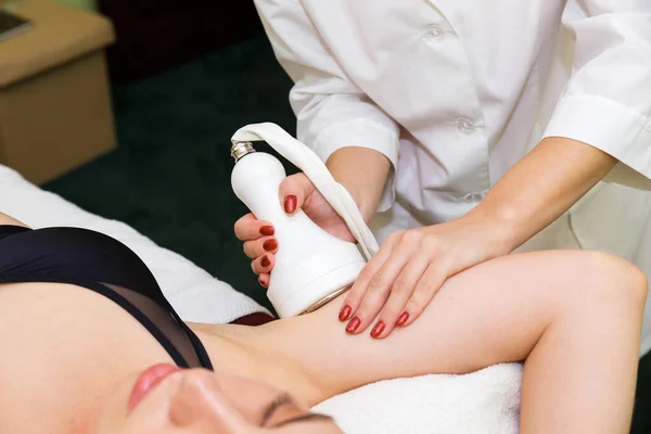 A young woman in an anti-cellulite procedure in a massage parlor. Anti-cellulite massage of the hand by cavitation.