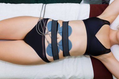Karnına miostimülasyon elektrotları yerleştirildi. Güzel bir dişi jigura için antielülit masaj miyostimülasyonu. Yukarıdan görünüm