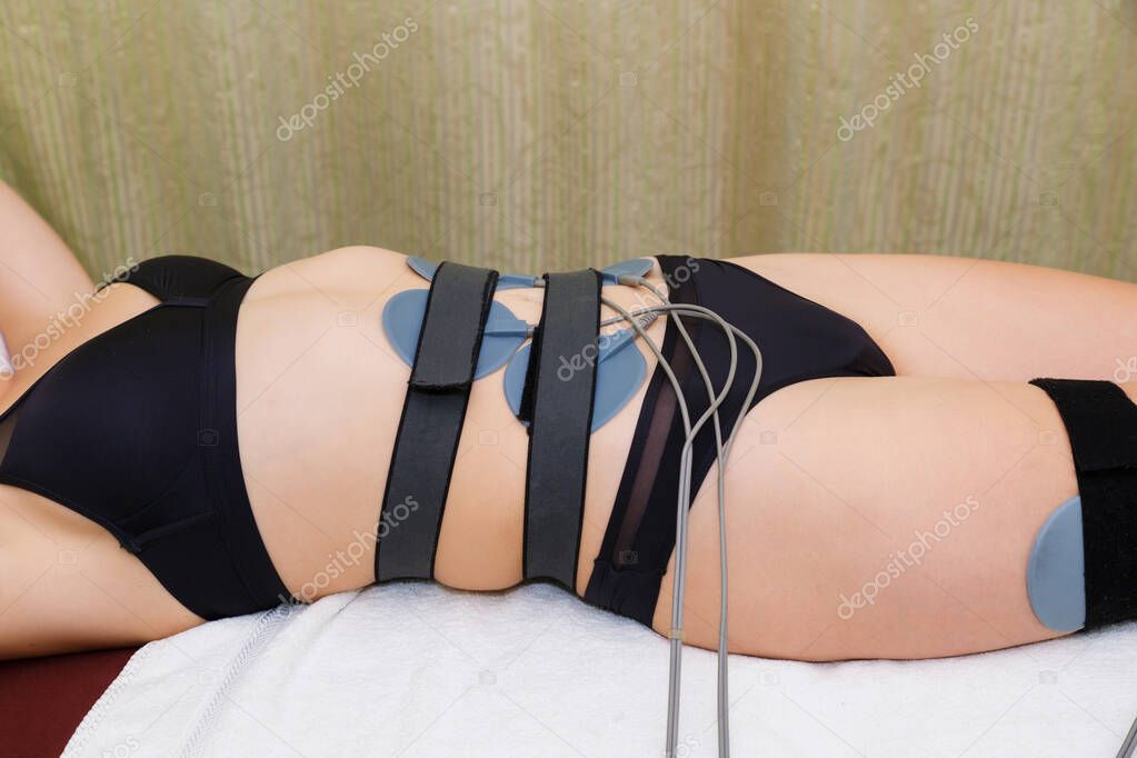 Myostimulation electrodes are installed on the abdominal muscles of a young woman. A slender woman undergoing muscle myostimulation.