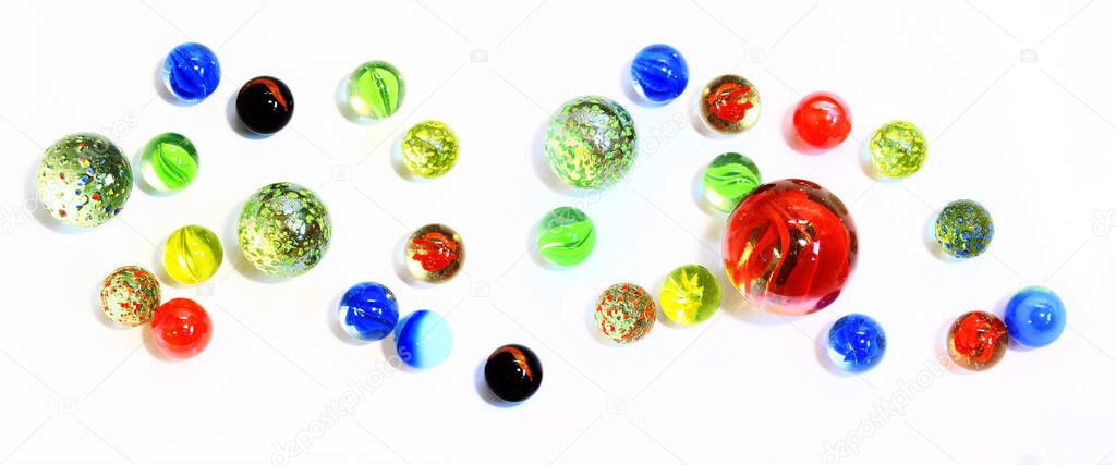 Top view of various multicolored glass marbles on white backgroun