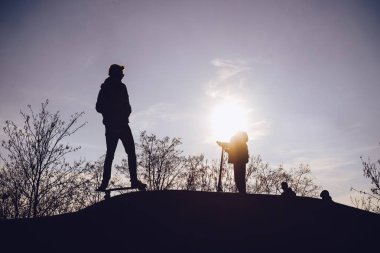 Çocukların gün batımında skate park siluetleri