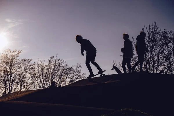 Силуэты детей в скейт-парке на закате — стоковое фото