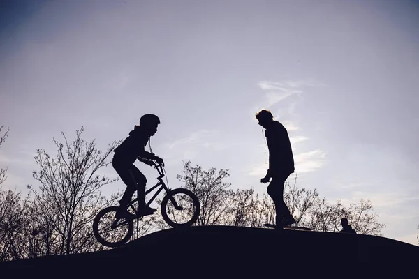 Silhouetten van kinderen in de skate-park bij zonsondergang — Stockfoto