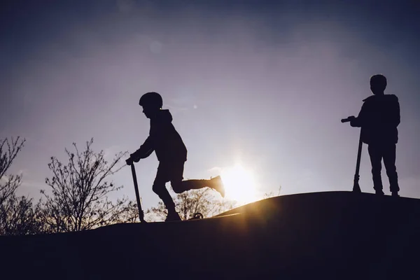 Siluetas de niños en el parque de skate al atardecer —  Fotos de Stock