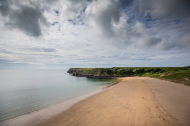 Birleşik Krallık, Galler'deki Pembrokeshire sahil şeridi üzerinde Barafundle Koyu'ndaki plajda yürüyüş yalnız çift