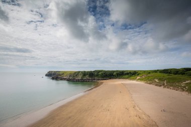 Galler'de Pembrokeshire sahil şeridi üzerinde Barafundle Koyu'ndaki plajda yürüyüş çiftler