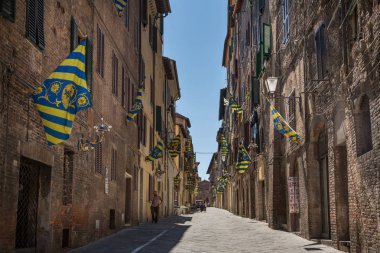 Siena Italy July 1st 2015 : Palio flags line a side street in Siena, Tuscany clipart
