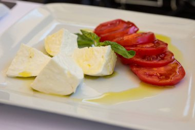Buffalo mozzarella peyniri, domates ve fesleğen salata sızma zeytinyağı ile giyinmiş.