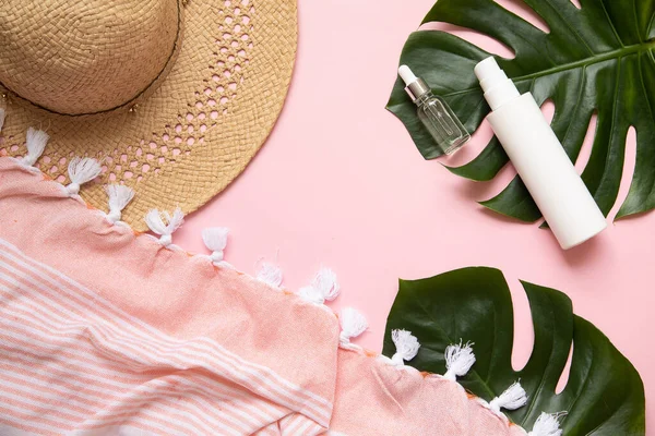 Folha de palmeira tropical sobre um fundo rosa. Protetor solar e chapéu em composição com folhas monstera.Vibrante conceito de moda mínima. — Fotografia de Stock