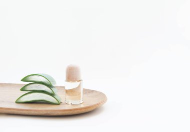 Beyaz arka planda esans şişesi ve aloe vera yaprakları.