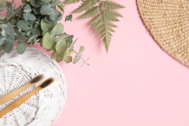 Bambu diş fırçası ve pembe arka planda okaliptüs yaprakları..