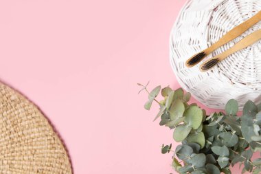 Bambu diş fırçası ve pembe arka planda okaliptüs yaprakları..