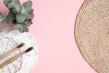 Bambu diş fırçası ve pembe arka planda okaliptüs yaprakları..