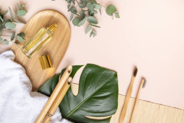 Bambu diş fırçası ve pembe arka planda okaliptüs yaprakları..