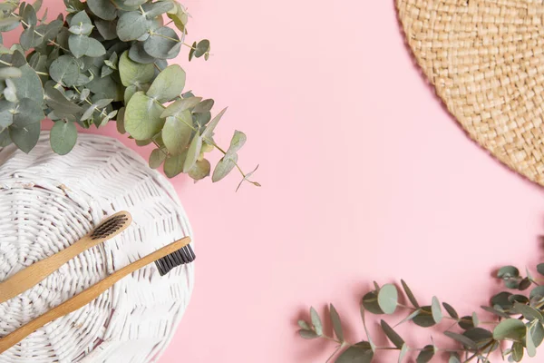 stock image Bamboo toothbrush and leaves of eucalyptus on pink background.