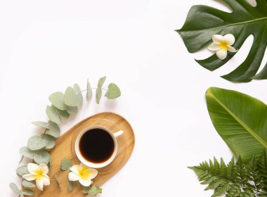 Taze tropik yapraklı bir fincan sade kahve..