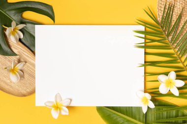 Sarı arka planda tropik palmiye yaprakları ve kağıt kart.