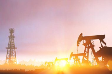 Gün batımında petrol kulesi ve pompaların siyah silueti
