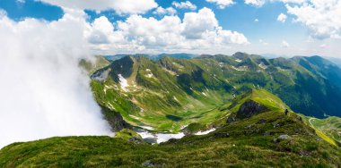 yükselen bulutlar ile Dağlık panorama. güzel manzara ile bazı kar çimenli yamaçlarda. Fagaras Romanya'nın Dağları hiking için popüler hedef