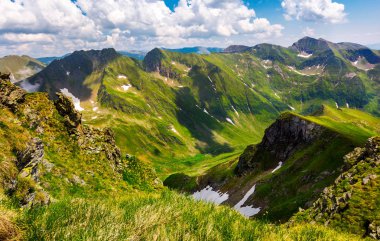 Yaz dağlarda kar Vadisi. Karpatlar muhteşem dağlık manzara. kayalık uçurum ve çimenli tepelerde bir bulutlu gökyüzü altında. Fagaras ridge, Güney Karpatlar, Romanya