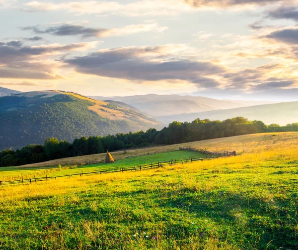 日出时山上美丽的乡村风光 干草堆在栅栏后面的田野上 过时的农业方法概念 — 图库照片