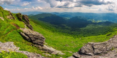 dağlık manzara güzel Panoraması. uçurumlar ile bir yamacın kenarına görüntüleyin. Borzhava ridge ve Runa dağ uzakta. Valley Village aşağı. güzel yaz sahne