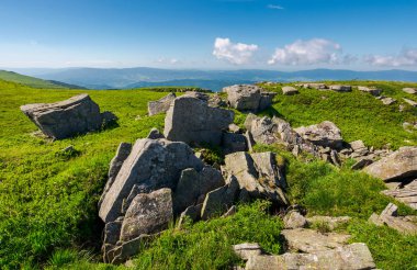 çimenli tepe üzerinde taşlar aralığı. güzel yaz yatay, kabarık bulutların üzerinde uzak dağ sırtı