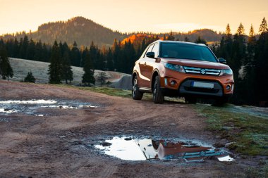 Apuseni, Romanya - 15 Ekim 2017: turuncu Suzuki Vitara Suv bir ülkede yol dağlar, gündoğumu. Ladin forest.travel Europe tarafından araba konsepti ile güzel sonbahar manzara