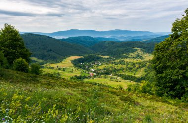 güzel kırsal manzara dağlarda. ormanlık tepeleri ve aşağı köyde vadi. bulutlu yaz manzara