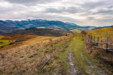 Kasım ayında kırsal alan. ahşap çit ülke karayoluyla. güçlü ridge uzakta karlı zirveleri ile. kasvetli sonbahar hava