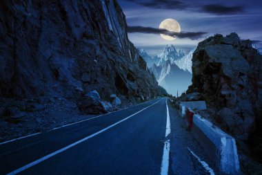 road in to the high mountains between rocky cliff at night in full moon light. composite image of dangerous path to the dreams.  clipart