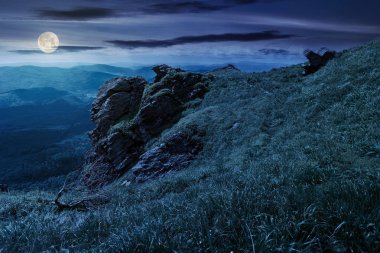 gece Rocky oluşumu çimenli bir tepenin üzerinde. yolu ot kayalar arasında. güzel dağ sırtı uzakta. Harika yaz hava. mavi gökyüzü üzerinde kabarık bulutlar