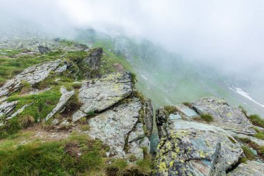 Fagaras ridge, kayalık uçurum kenarında. Romen dağlık bölgelerde kalın sis gizemli toplayan. güzel yaz manzara. Popüler seyahat hedef. birkaç turist uzaktan
