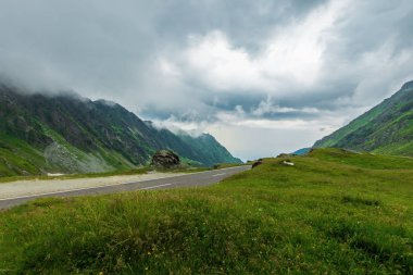 fırtınalı havalarda Transfagarasan yol. Romanya'nın popüler seyahat hedef. bir tepenin kenarında otsu çayır boyunca. uzak Vadisi'ne görüntüleyin. bulutlu gökyüzü