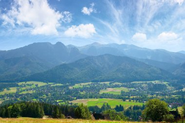 Zakopane yaz manzarası. Gubalowka 'dan uzak Tatra dağlarına güzel bir manzara. Polonya 'nın popüler seyahat merkezi. Güneşli bir hava, bulutlu muhteşem tepenin üstünde.