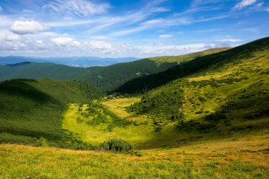 Yaz dağlarının tepeleri ve vadisi. Mavi gökyüzünde bulutlu güneşli bir hava. Benekli ışıkta güzel bir kornohora tepesi manzarası.