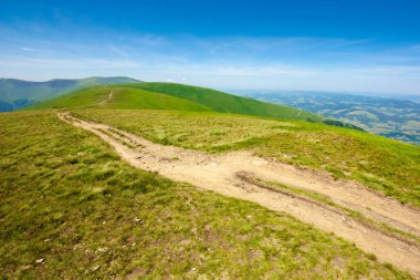 Çimenli çayır boyunca dağ yolu. Harika bir yaz macerası. Mavi gökyüzündeki bulutlar