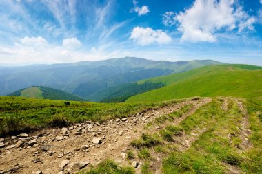 Çimenli çayır boyunca dağ yolu. Harika bir yaz macerası. Mavi gökyüzündeki bulutlar
